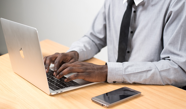 a man using a laptop computer sitting on top of a table